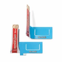 Hyllkantspratare i papp, som fäst på hyllkanten runt prisskylten. Den lilla flärpen nedtill fäst med dubbelhäftande tejp vid montering, så att den figurstansade produkten sticker ut 90 grader från hyllan.